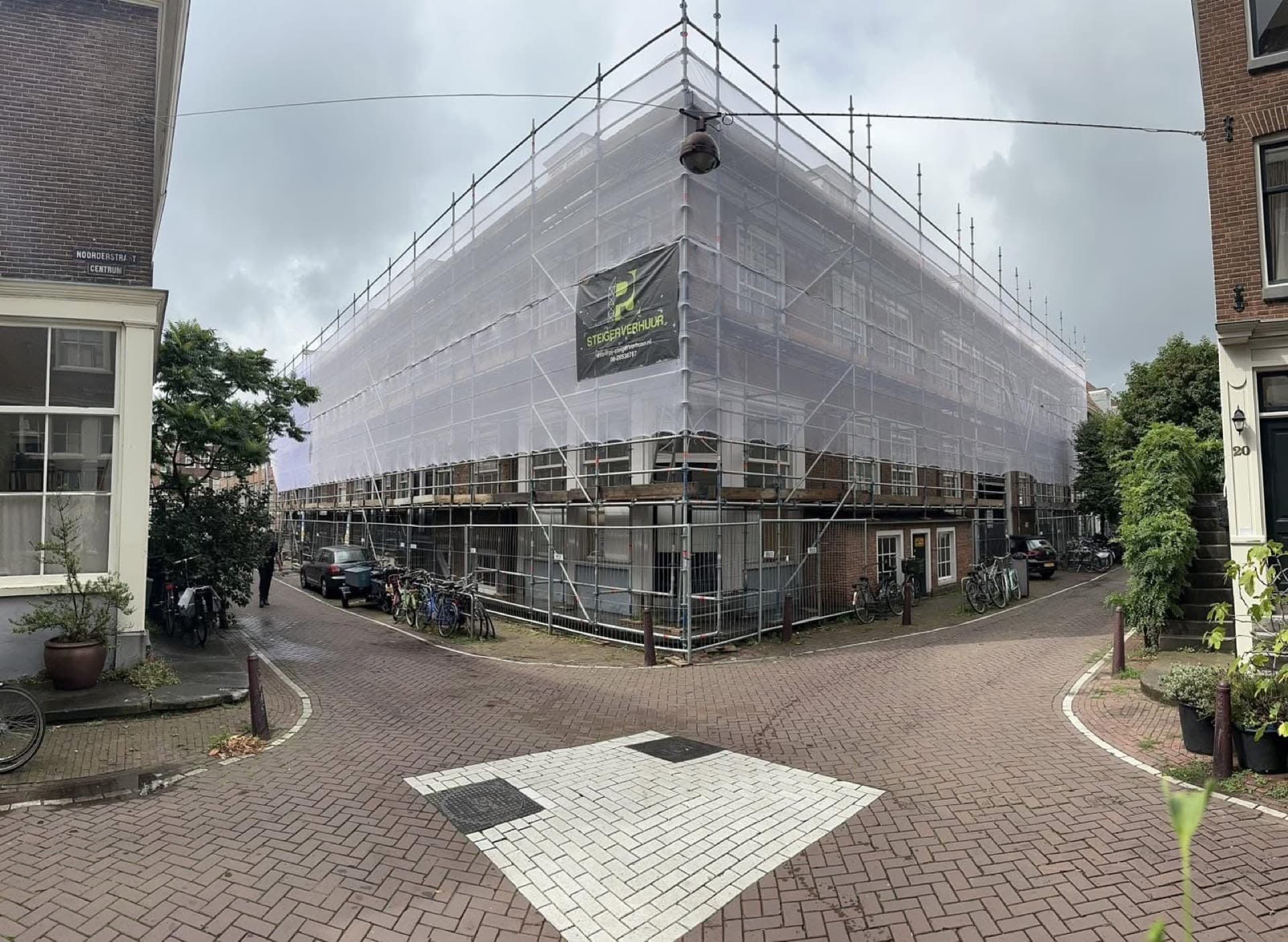 Steigerconstructie met PJ Steigerverhuur banner bij hoekpand voor gevelonderhoud