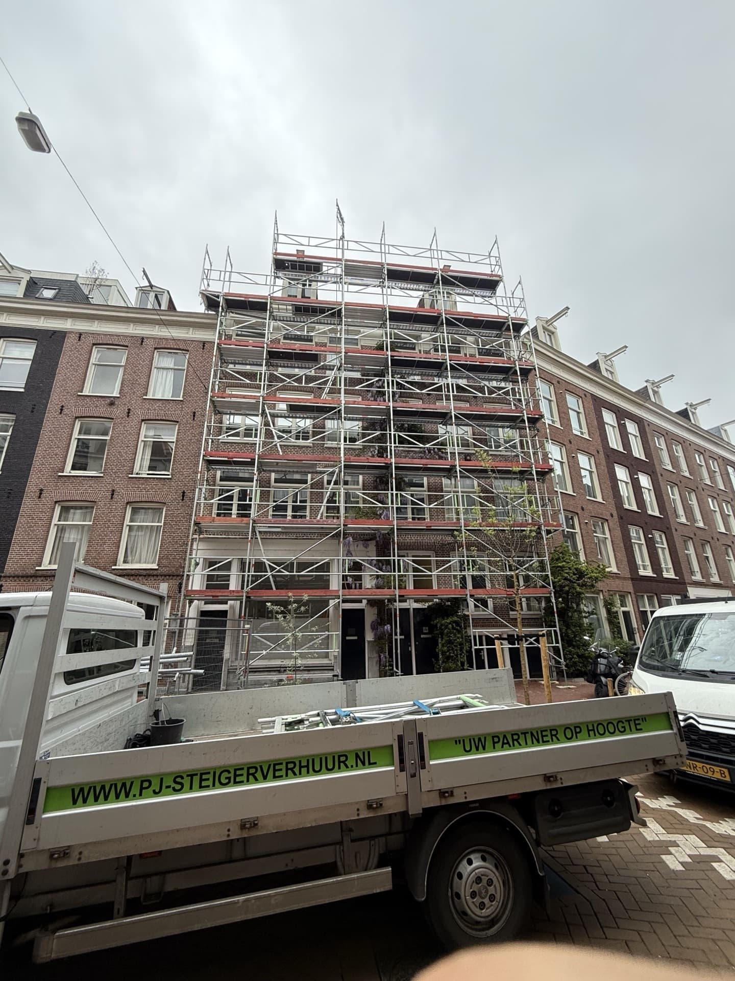 PJ Steigerverhuur vrachtwagen met bedrijfslogo bij gevelsteiger in Amsterdam